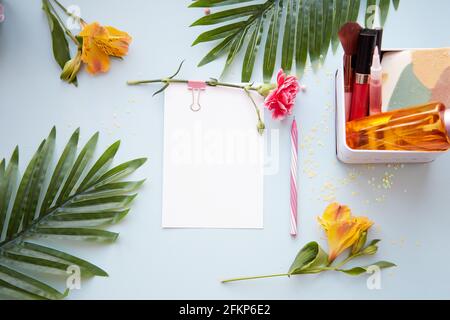 Sommer Beauty-Konzept Hintergrund mit Schreibwarenkarte, Stift, tropischen Blättern, Kosmetikprodukten und Alstroemeria Blumen. Hochwertige Fotos Stockfoto