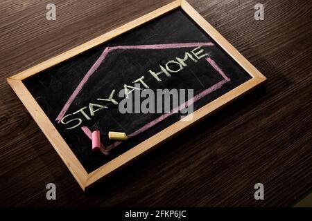 Bleib zu Hause Wort auf Tafel geschrieben in Kreide, Coronavirus-Konzept. Stockfoto