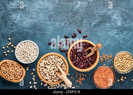 Hülsenfrüchte, Linsen, Kichererbsen, Bohnen-Sortiment, leckere appetitliche Zutaten Gewürze Lebensmittel zum Kochen gesunde Küche auf schwarzem Tisch. Gewichtsverlust Ernährung Stockfoto