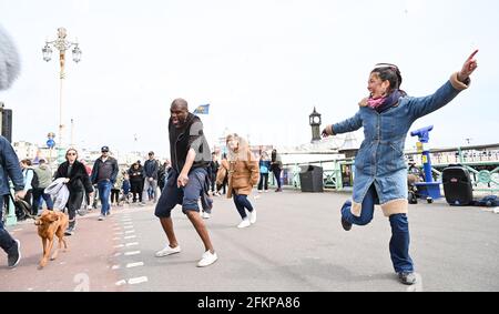 Brighton UK 3. Mai 2021 - Dancing in the Street on Brighton Seafront as visitors enjoy the May Bank Holiday trotz des windigen Wetters : Credit Simon Dack / Alamy Live News Stockfoto