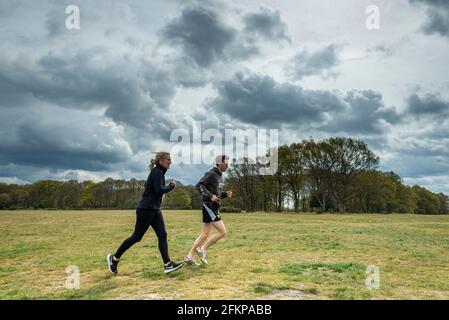 Chorleywood, Großbritannien. 3 Mai 2021. Wetter in Großbritannien: Ein Paar, das am Montag, den frühen Bankfeiertag im Mai, unter ominösen grauen Wolken über Chorleywood Common, Hertfordshire, läuft. Es wird prognostiziert, dass sich die Bedingungen gegen Ende des Tages mit starken Regenfällen und starken Winden verschlechtern werden. Kredit: Stephen Chung / Alamy Live Nachrichten Stockfoto