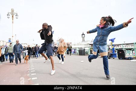 Brighton UK 3. Mai 2021 - Dancing in the Street on Brighton Seafront as visitors enjoy the May Bank Holiday trotz des windigen Wetters : Credit Simon Dack / Alamy Live News Stockfoto