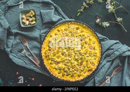 Hausgemachte Rhabarbertarte und Frühlingsdekoration auf dunkelgrauem Hintergrund, Draufsicht Stockfoto