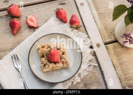 Ein Stück Rhabarber zerbröselter Kuchen und Erdbeeren auf einem Teller Auf einem alten Holztisch Stockfoto