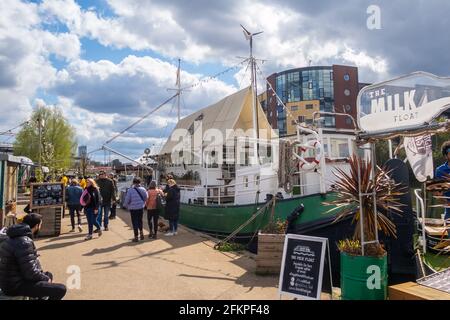 LONDON, Großbritannien - 11. APRIL 2021: Menschen vor den Grachtenbooten in Hackney Wick in London an einem sonnigen Tag. Stockfoto