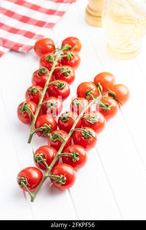 Frische rote Kirschtomaten. Kleine Tomaten auf Zweig auf weißem Tisch. Stockfoto