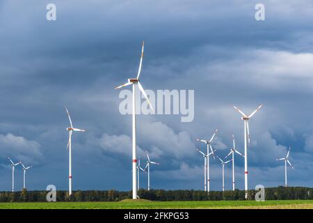 Windturbinen im offenen Gelände an windigen Tagen mit dunklen Wolken am Himmel. Alternative Stromerzeugung. Stockfoto