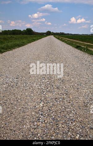 Die Straße wird von einem gepflügten Feld in der italienischen Landschaft begrenzt Stockfoto