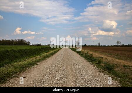 Die Straße wird von einem gepflügten Feld in der italienischen Landschaft begrenzt Stockfoto