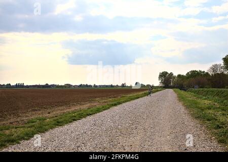 Die Straße wird von einem gepflügten Feld in der italienischen Landschaft begrenzt Stockfoto