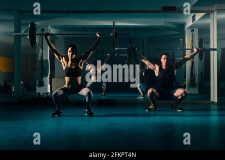 Ein Workout-Paar Training im Fitnessstudio und tun Overhead hockt Übung mit Gewicht auf der Langhantel. Stockfoto