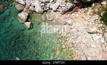 Luftdrohnen-Ansichten über eine felsige Küste, kristallklares ägäisches Meer, touristische Strände und viel Grün an einem wolkenlosen Tag in Skopelos isla Stockfoto