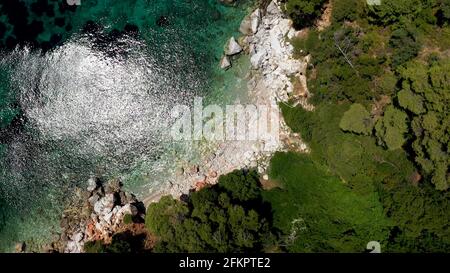 Luftdrohnen-Ansichten über eine felsige Küste, kristallklares ägäisches Meer, touristische Strände und viel Grün an einem wolkenlosen Tag in Skopelos isla Stockfoto