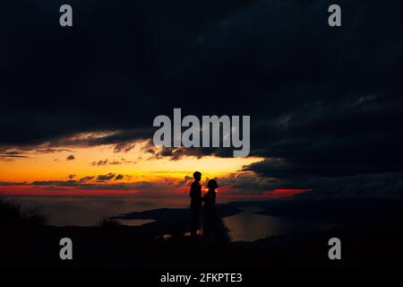 Bräutigam und Braut halten bei Dämmerung die Hände auf dem stehen Meeresküste Stockfoto