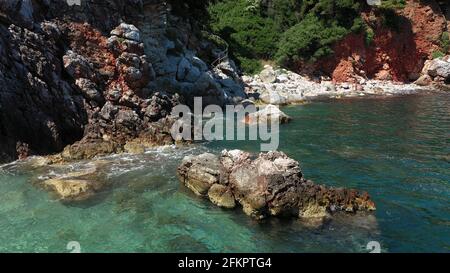 Luftdrohnen-Ansichten über eine felsige Küste, kristallklares ägäisches Meer, touristische Strände und viel Grün an einem wolkenlosen Tag in Skopelos isla Stockfoto