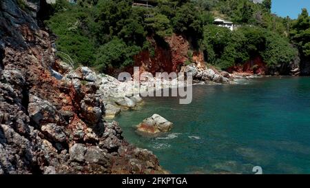 Luftdrohnen-Ansichten über eine felsige Küste, kristallklares ägäisches Meer, touristische Strände und viel Grün an einem wolkenlosen Tag in Skopelos isla Stockfoto