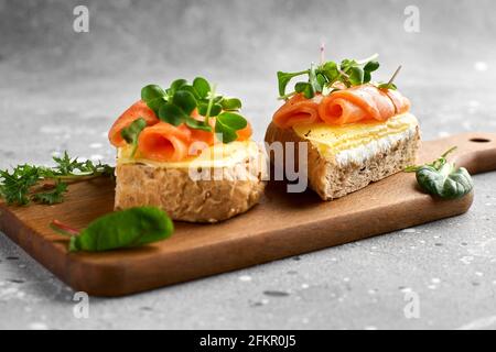 Bruschetta mit Lachs. Vollkornbrot mit Lachs, Käse auf einem Holzbrett. Nahaufnahme. Stockfoto