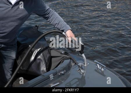 Der Mensch hat eine Kraftstoffpistole in der Hand und füllt den Tank seines Bootes mit Benzin. Konzentrieren Sie sich auf den Tankeinfüllstutzen und den Deckel Stockfoto