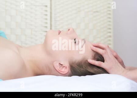 Schöne junge Frau bekommt Gesichtsmassage im Schönheitssalon, Nahaufnahme Porträt, Seitenansicht Stockfoto