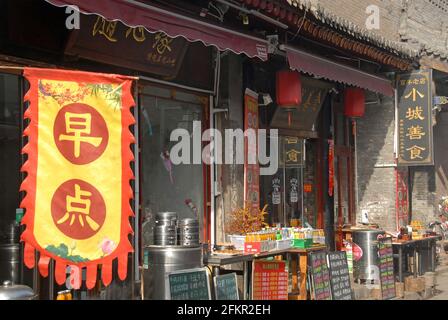 Kleine chinesische Restaurants in einer Seitenstraße in Pingyao, Provinz Shanxi, China. Menütafeln befinden sich vor den Restaurants. Stockfoto