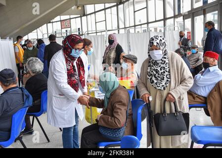 Tunis, Tunesien. Mai 2021. Ein tunesischer Gesundheitshelfer unterstützt eine ältere Frau bei der Impfung in der Sporthalle El-Menzah in der tunesischen Hauptstadt. Kredit: SOPA Images Limited/Alamy Live Nachrichten Stockfoto