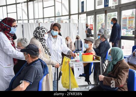 Tunis, Tunesien. Mai 2021. Ein tunesischer Gesundheitshelfer unterstützt eine ältere Frau bei der Impfung in der Sporthalle El-Menzah in der tunesischen Hauptstadt. Kredit: SOPA Images Limited/Alamy Live Nachrichten Stockfoto