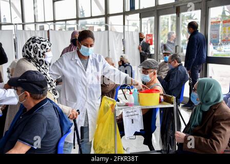 Tunis, Tunesien. Mai 2021. Ein tunesischer Gesundheitshelfer unterstützt eine ältere Frau bei der Impfung in der Sporthalle El-Menzah in der tunesischen Hauptstadt. Kredit: SOPA Images Limited/Alamy Live Nachrichten Stockfoto