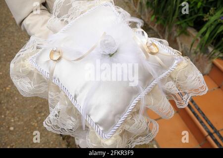 Goldene und silberne Ringe auf einem Stoffkissen mit Blumendekor platziert. Stockfoto