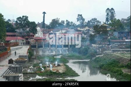 Kathmandu, Nepal. Mai 2021. Nepalesische Männer werden mit persönlicher Schutzausrüstung (PSA) gesehen und äschern die Leichen eines COVID-19-Opfers am Ufer des Bagmati-Flusses ein. Die nepalesische Regierung Verbot alle nationalen und internationalen Flüge bis zum 14. Mai 2021, da die Zahl der COVID-19-Fälle im Land weiter ansteigt. Kredit: SOPA Images Limited/Alamy Live Nachrichten Stockfoto