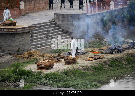 Kathmandu, Nepal. Mai 2021. Nepalesische Männer werden mit persönlicher Schutzausrüstung (PSA) gesehen und äschern die Leichen eines COVID-19-Opfers am Ufer des Bagmati-Flusses ein. Die nepalesische Regierung Verbot alle nationalen und internationalen Flüge bis zum 14. Mai 2021, da die Zahl der COVID-19-Fälle im Land weiter ansteigt. Kredit: SOPA Images Limited/Alamy Live Nachrichten Stockfoto