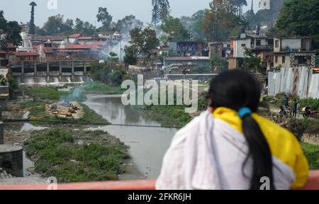 Kathmandu, Nepal. Mai 2021. Ein Familienmitglied beobachtet, wie nepalesische Arbeiter mit persönlicher Schutzausrüstung (PSA) die Körper der Covid-19-Opfer am Ufer des Bagmati-Flusses einäschern. Die nepalesische Regierung Verbot alle nationalen und internationalen Flüge bis zum 14. Mai 2021, da die Zahl der COVID-19-Fälle im Land weiter ansteigt. (Foto von Sunil Pradhan/SOPA Images/Sipa USA) Quelle: SIPA USA/Alamy Live News Stockfoto