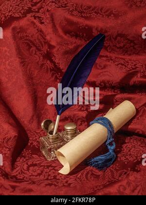 Blaue Federkiel, Glasinkwell und Pergament auf einem roten Damasttuch, auf einem Foto, das Sie in die Zeit zurückversetzt Stockfoto