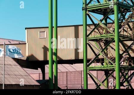 Containerterminal der TIS Group Ukraine größten Trockenfrachthafen. Metallturm Treppe in grüner Farbe auf geripptem Lagerhaus Wand Hintergrund und Flagge gemalt Stockfoto