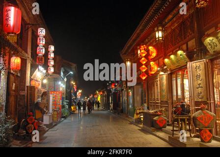 Pingyao in der Provinz Shanxi, China: Straßenszene in Pingyao bei Nacht mit Stadtlichtern und roten Laternen. Stockfoto