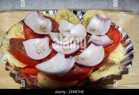 Roher Zwiebel-, Tomaten- und Gurkensalat. Masala-Pulver und schwarzer Pfeffer bestreut und auf dem Teller serviert. Indische Street Food Snacks Salat Stockfoto