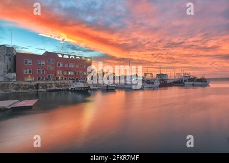 Fischerboote in der Stadtbucht von Monopoli bei Sonnenuntergang mit bewölktem Himmel im Hintergrund, Süditalien, Europa Stockfoto