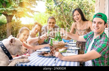 Eine Gruppe von glücklichen Freunden, die beim Gartengrill essen und toasten - Konzept des Glücks mit jungen Menschen zu Hause genießen Essen zusammen Stockfoto