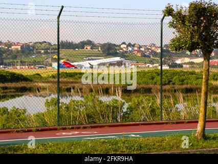 Ein Iberia-Passagierjet hebt vom Flughafen Santander ab, der nach Madrid fährt, und blickt vom Umzäunungszaun aus mit einem Radfahrer, der an Spanien vorbeifährt Stockfoto