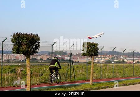 Ein Iberia-Passagierjet hebt vom Flughafen Santander ab, der nach Madrid fährt, und blickt vom Umzäunungszaun aus mit einem Radfahrer, der an Spanien vorbeifährt Stockfoto