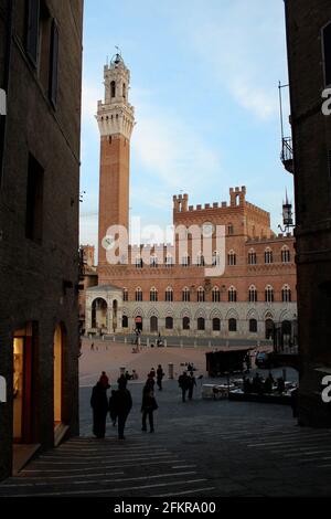 Blick von der Gasse auf die Piazza del Campo, den Mangia-Turm und den Palazzo Pubblico in Siena, Toskana, Italien Stockfoto