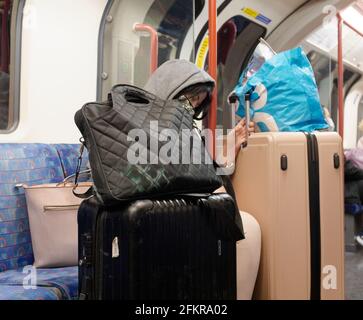 London, Greater London, England - 27 2021. April: Eine einreisende Person in der U-Bahn hält sich an ihr überflüssiges Gepäck fest. Stockfoto