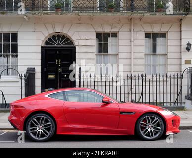 London, Greater London, England - Apr 27 2021: Roter Sportwagen vor einem Wohngrundstück mit Geländer und Balkon geparkt. Stockfoto