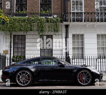 London, Greater London, England - 27 2021. Apr: Schwarzer Porsche parkte vor einer Wohnimmobilie mit Geländern. Stockfoto