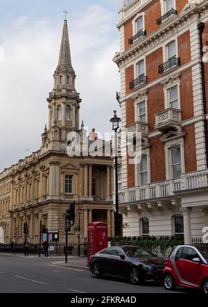 London, Greater London, England - Apr 27 2021: Hinde Street Methodist Church mit einer traditionellen roten Telefonbox und Wohnimmobilien in der Nähe. Stockfoto