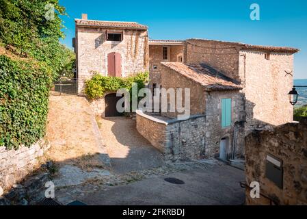 Typische Straße von Menerbes in Frankreich, mit Steinhäusern, Pflanzen und Holzfenstern Stockfoto