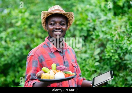 Afrikanischer Landwirt, der ein Gemüsepaket hält. Bio-Gemüse bereit, um in Salat Lieferservice zu dienen Stockfoto