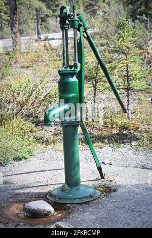 Eine altmodische Handpumpe mit grünem Wasser Stockfoto