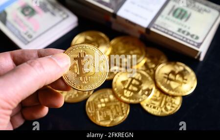 Bitcoin mit Dollar-Cash-Stacks, digitaler virtueller Krypto-Währung Bitcoin (btc) und Papiergeld. Eine Goldbitmünze in der Hand auf Geldhintergrund. Konzept Stockfoto