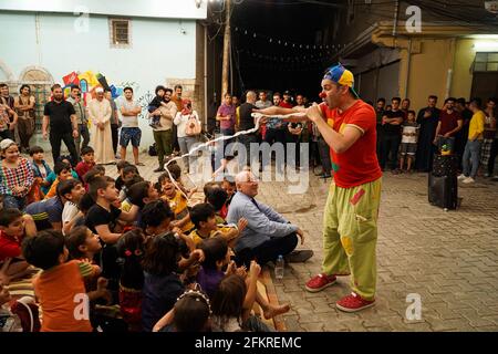 Iraqi Children interagieren mit einem italienischen Clown, der eine Unterhaltungsshow für sie vorführt.eine Unterhaltungsshow wird vom italienischen Clown Marco Rodari inszeniert, Bekannt als Claun il Pimpa für Kinder in der Hammam Al-Manqusha-Gegend in der Altstadt von Mossul, um ihnen zu helfen, mit den Auswirkungen des Krieges und der Besetzung der Stadt durch den IS (Islamischer Staat des Irak und Syrien) fertig zu werden. Die Show fand in dieser fröhlichen blauen Gasse statt, die vor kurzem von Jugendlichen Freiwilligen neu organisiert und arrangiert wurde, um eine wunderschöne Fassade des Gebiets zu werden, das sich nach der Zerstörung durch den letzten Krieg erholt hat. Stockfoto