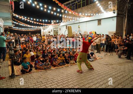 Iraqi Children interagieren mit einem italienischen Clown, der eine Unterhaltungsshow für sie vorführt.eine Unterhaltungsshow wird vom italienischen Clown Marco Rodari inszeniert, Bekannt als Claun il Pimpa für Kinder in der Hammam Al-Manqusha-Gegend in der Altstadt von Mossul, um ihnen zu helfen, mit den Auswirkungen des Krieges und der Besetzung der Stadt durch den IS (Islamischer Staat des Irak und Syrien) fertig zu werden. Die Show fand in dieser fröhlichen blauen Gasse statt, die vor kurzem von Jugendlichen Freiwilligen neu organisiert und arrangiert wurde, um eine wunderschöne Fassade des Gebiets zu werden, das sich nach der Zerstörung durch den letzten Krieg erholt hat. Stockfoto